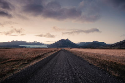 Road leading towards mountains against sky