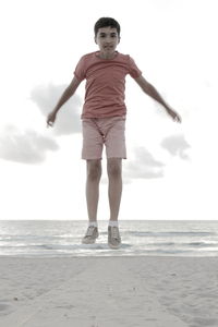 Full length of happy boy on beach against sky