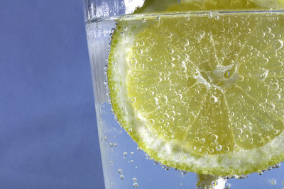 Close-up of lemon drink in glass against blue background