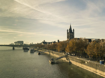 Bridge over river by buildings against sky in city