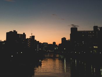 Illuminated buildings in city at sunset