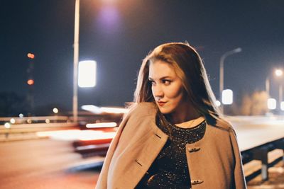 Young woman standing on street at night