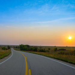 Road amidst landscape against sky during sunset