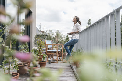 Smiling woman relaxing on balcony holding tablet