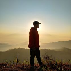 Man standing on mountain against sky during sunset