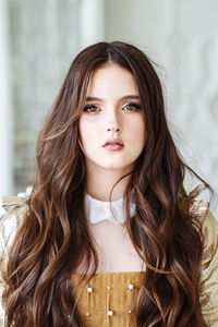 Portrait of beautiful young woman with long dark hair. golden retro dress