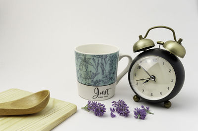 Close-up of clock on table against white background