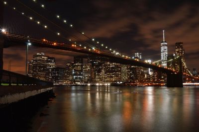 Low angle view of illuminated brooklyn bridge over river against sky at night