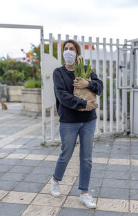 Full length portrait of woman standing on footpath