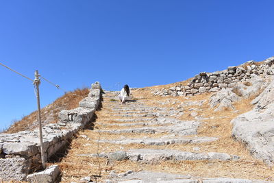 Low angle view of people on mountain against clear blue sky