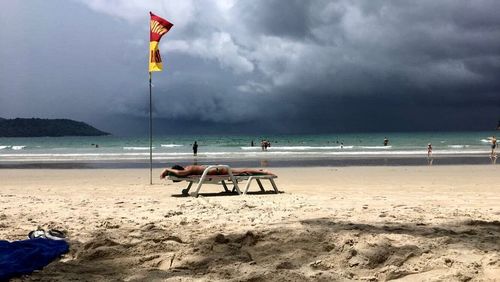 Lifeguard hut on beach against cloudy sky