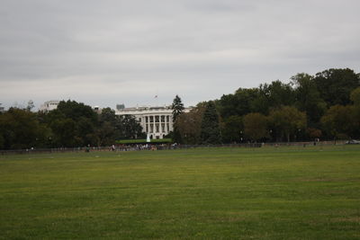 Trees in lawn against cloudy sky