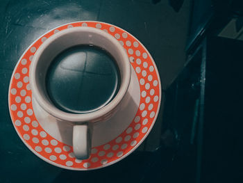 A cup of black coffee with a polka dot glass motif on a black background
