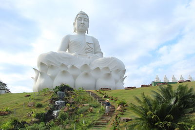 Unidentified tourist walking in front of the second largest buda statue in the world in ibiraçu