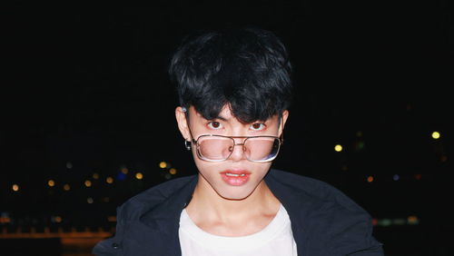 Portrait of young man wearing eyeglasses at night