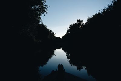 Silhouette trees by lake against sky during sunset