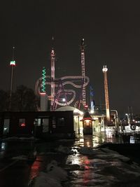 Illuminated amusement park against sky at night