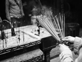 Cropped hand of woman holding incense sticks