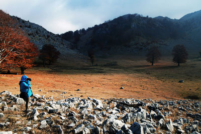 Side view of woman photographing mountain during autumn