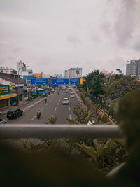 Cars on road by buildings in city against sky