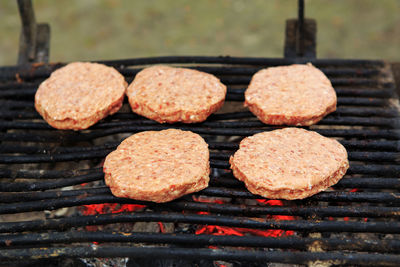 Closeup macro of five raw meat barbecue hamburgers on grill fire