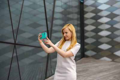 Young blond woman making selfie on smartphone for her followers. young influencer girl. 