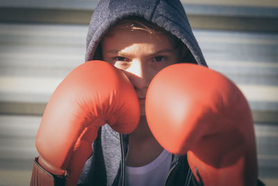 Close-up portrait of boy wearing red boxing gloves outdoors