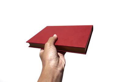 Close-up of hand holding book against white background