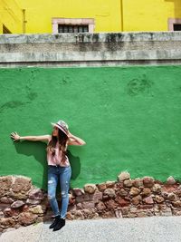 Full length of woman standing against wall