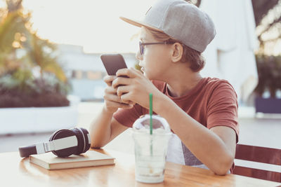 Boy using phone while sitting at table