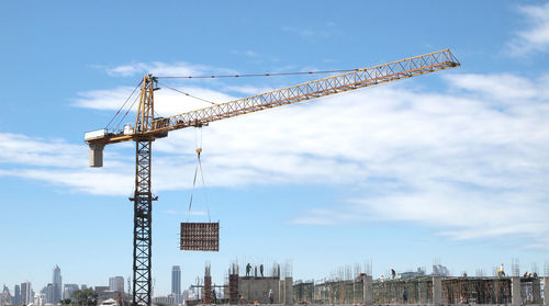 Cranes at construction site against sky in city