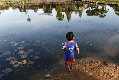 Rear view of boy standing in lake