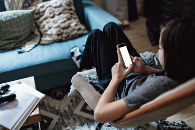 High angle view of boy using mobile phone while sitting in living room