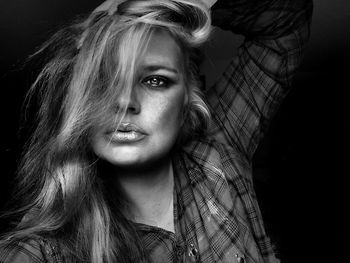 Close-up portrait of beautiful woman against black background