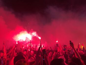 Crowd enjoying while holding distress flare music concert at night