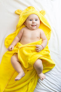 Portrait of cute baby girl lying on bed at home