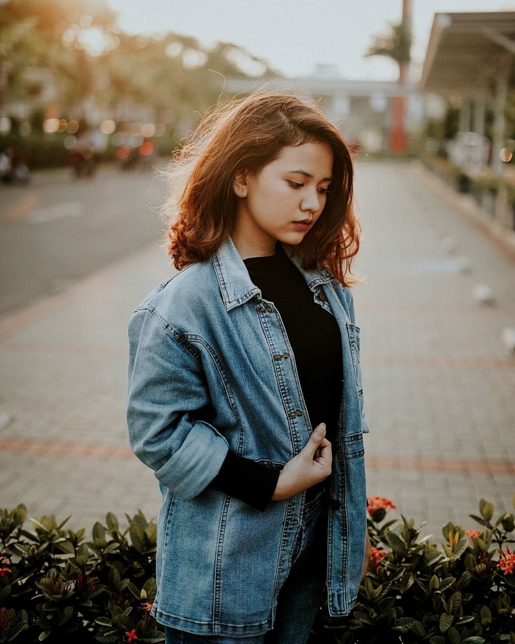 YOUNG WOMAN LOOKING UP WHILE STANDING OUTDOORS