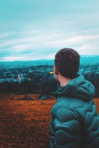 Rear view of man looking at cityscape against sky