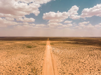 Drone aerial of camper van traveling through vast  outback landscape with dust storm on the horizon