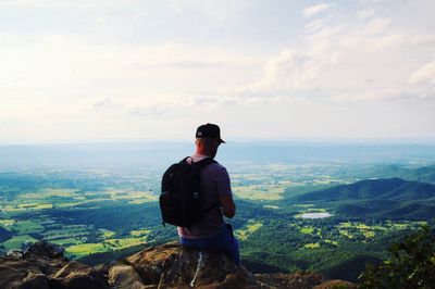 Rear view of man looking at mountains against sky