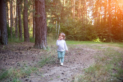 Full length of smiling girl standing in forest