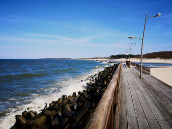 A wooden walkway by a baltic coastline with a pile of tetra-pods for sea defence/defense