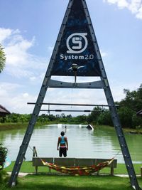 Rear view of man standing in water against sky