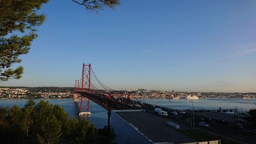 Suspension bridge over river in city against blue sky