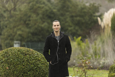 Portrait of young man standing against trees