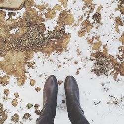 Low section of person wearing boots standing on snow covered field