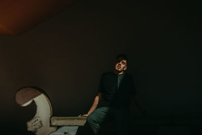 Portrait of smiling woman standing against black background