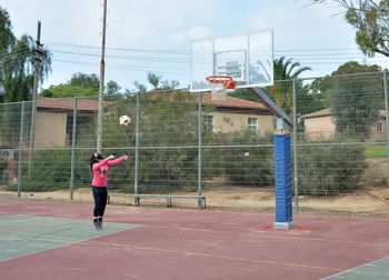 Man playing basketball hoop against trees