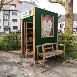 Empty chairs and tables on sidewalk by building