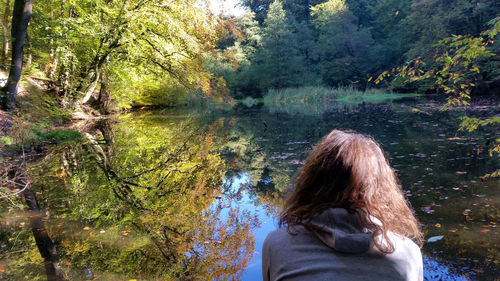 Rear view of man relaxing against trees